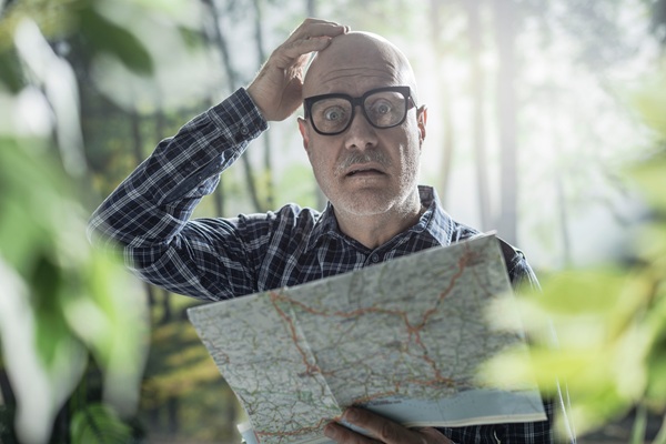 Mann mit Landkarte auf der Suche nach Orientierung im Wald