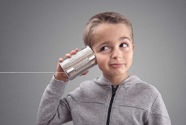 Kind hält eine Blechdose wie ein Telefon ans Ohr