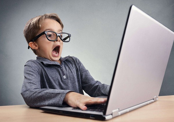 Überraschtes Kind mit Brille vor einem Laptop